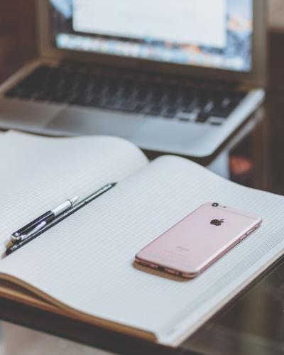 an open notebook on a desk in front of a laptop with a cup of coffee to the right