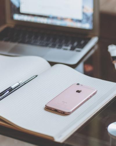 an open notebook on a desk in front of a laptop with a cup of coffee to the right